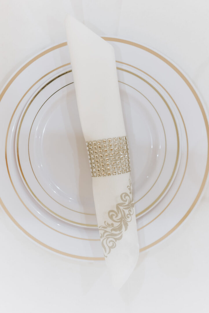 a white plate with golden border, and a napkin on it